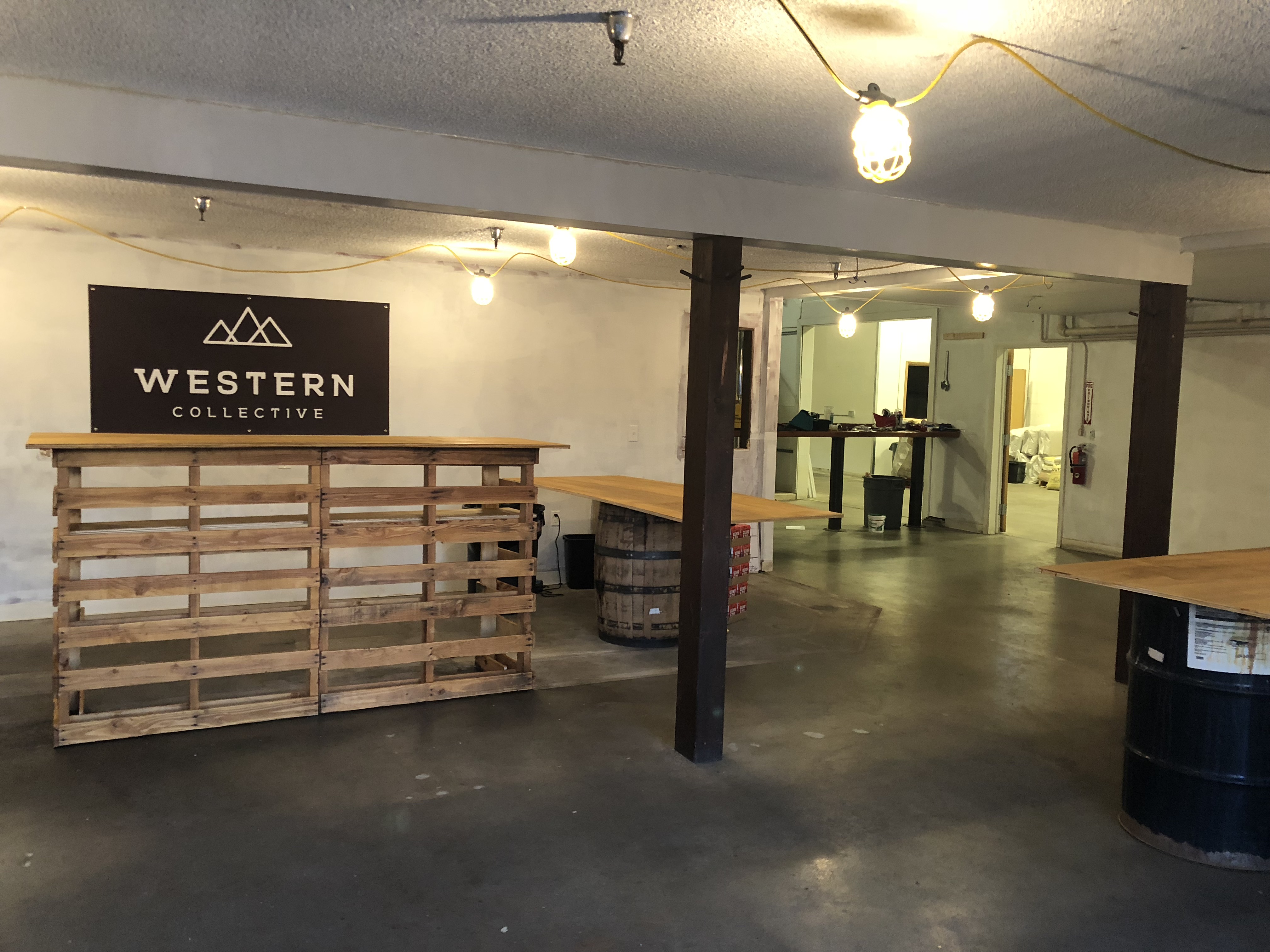 Western Collective, early-stage lounge with pallet bar and work lights.